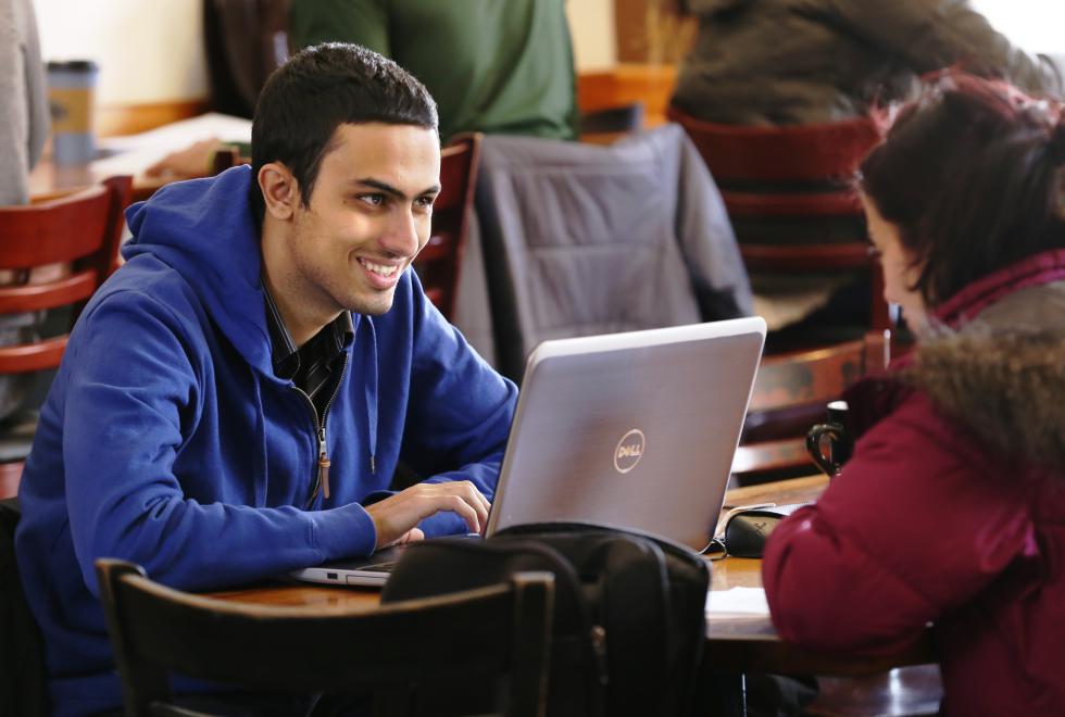 MICKY BEDELL Amir Tofighi, 23, of Texas smiles at his girlfriend while working on his computer at Rao's Coffee and Cafe in Amherst on Wednesday, March 18. - MICKY BEDELL | DAILY HAMPSHIRE GAZETTE