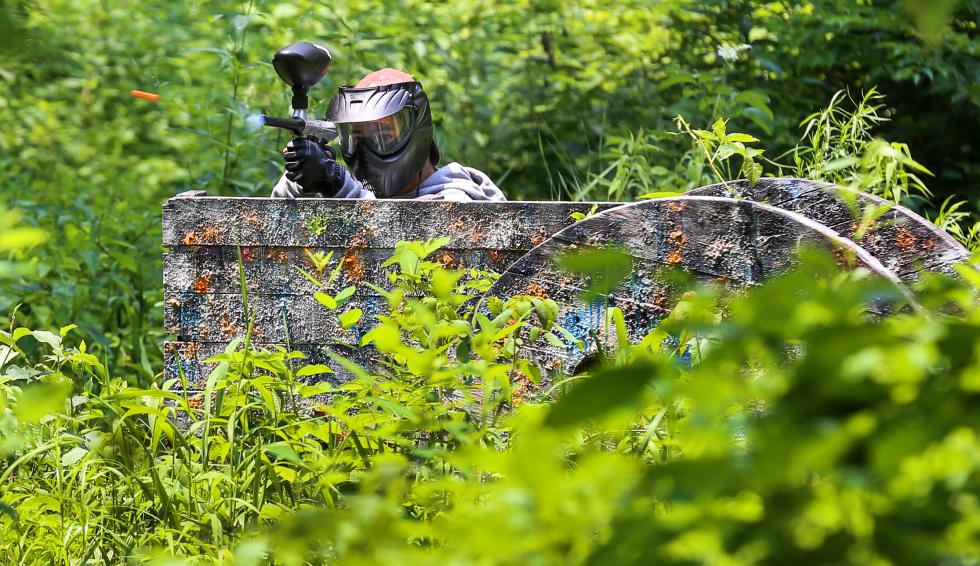 MICKY BEDELL A paintballer crouches, firing from behind a wooden barrier on a field at Agawam Xtreme Paintball on Sunday afternoon. - Micky Bedell |
