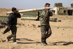Alexander KotsFILE - In this file photo taken on Wednesday, Feb. 17, 2016, soldiers from the Syrian army carry a rocket to fire at Islamic State group positions in the province of Raqqa, Syria. A two-pronged advance to capture key urban strongholds of the Islamic State, and the extremist group's self-styled capital of Raqqa has underlined a convergence of strategy between Washington and Moscow to defeat the extremist group, with Syria's Kurds emerging as the common denominator. (Alexander Kots/Komsomolskaya Pravda via AP, File)