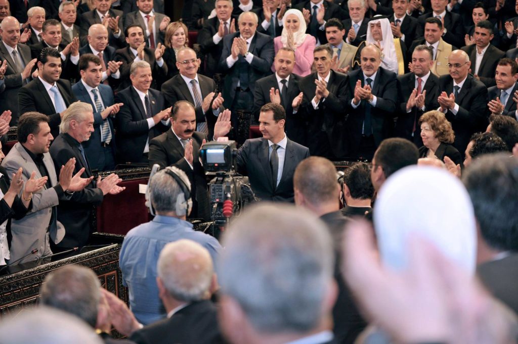 HOEPIn this photo released on the official Facebook page of the Syrian Presidency, Syrian President Bashar Assad, center, waves on his arrives to addresses the newly-elected parliament, as lawmakers applaud him, at the parliament building, in Damascus, Syria, Tuesday, June 7, 2016. Assad has vowed to liberate every inch of the country the way government forces captured the historic town of Palmyra from the Islamic State group. (AP Photo/Syrian Presidency via Facebook)