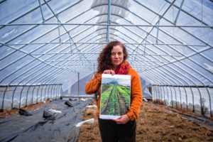 Deb Habib, owner of Seeds of Solidarity with her husband Ricky Baruc, stands on her property holding one of her photographs which will be featured in her family's upcoming exhibition with other pieces made by Ricky Baruc and her son Levi Baruch, titled "Seeking the Sacred on the Farm" at the UMass Fine Arts Center which opens Thursday, February 9.
