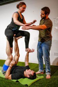 Etai Dvora of Northampton, right, spots as Hampshire College student Elizabeth Levick, top, and Jason Potash of Northampton transition from straddle throne to easy throne March 31, 2017 during an acroyoga meet up at Mill 180 Park in Easthampton.