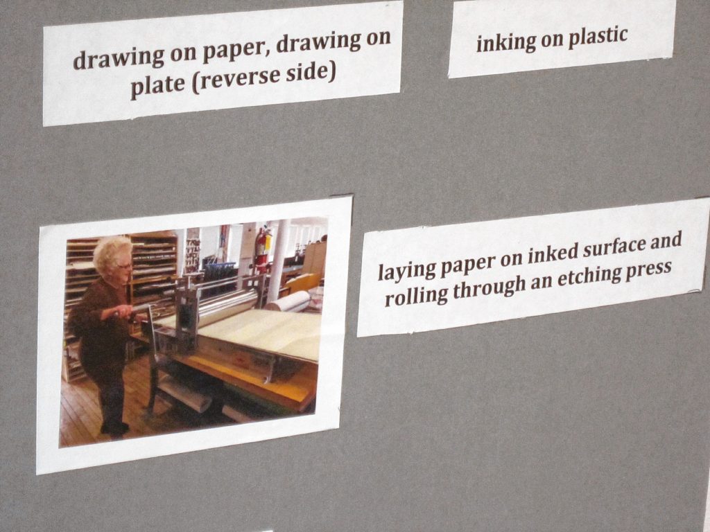 Doris Madsen is seen here laying paper on an inked surface and rolling through an etching process to create her artwork. 