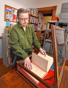 Ben Power Alwin opens a case that displays a copy of "The World is Round" that is signed by author Gertrude Stein and illustrator Clement Hurd, at the Sexual Minorities Archives in Holyoke, Tuesday, April 23, 2019.