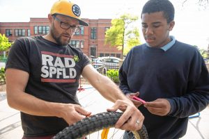 Alex Weck, a RAD of Springfield project manager, works with Dwight Griffin to change a tire on a bike.