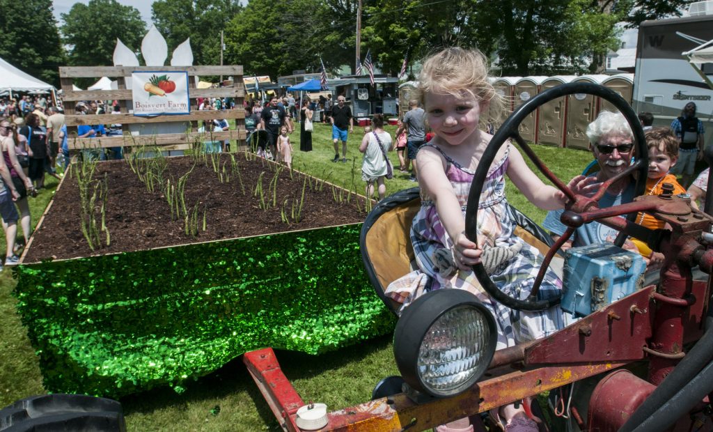 Fiona McNutt, 4, of Amherst takes a turn sitting in the driver's seat of a McCormick Farmall tractor that pulled the Boisvert Farm asparagus float to the WGBY Asparagus Festival on the Hadley Town Common on Saturday, June 2, 2018.