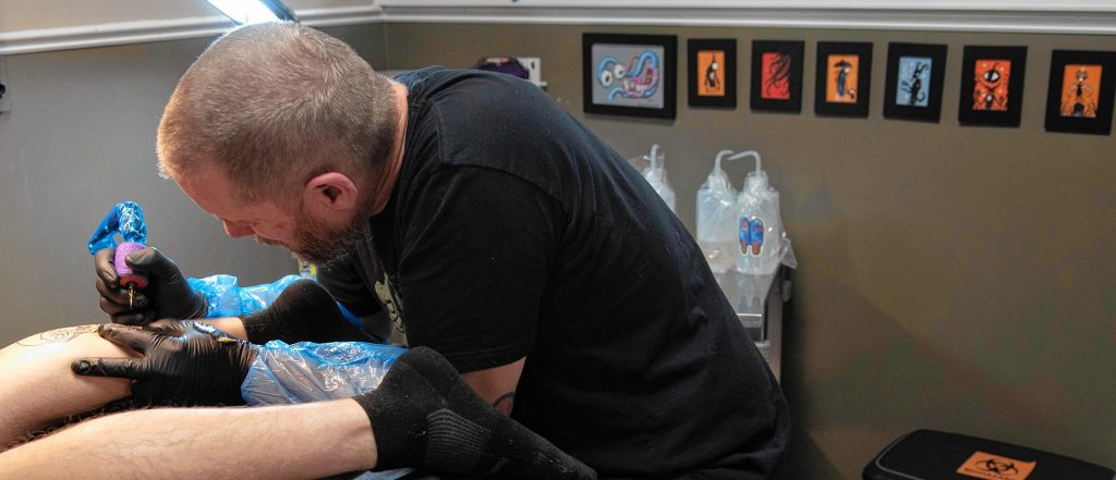 Eric Talbot works on a tattoo for Matt Miller at Oxbow Tattoo in Easthampton.