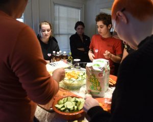 Rafaella Fabrizi, Joelle Bueno, and Emma Kinney, watch as Natty demonstrates how to make pupusas as a collaboration between the Trans Asylum Seeker Support Network and a University of Massachusetts anthropology class.