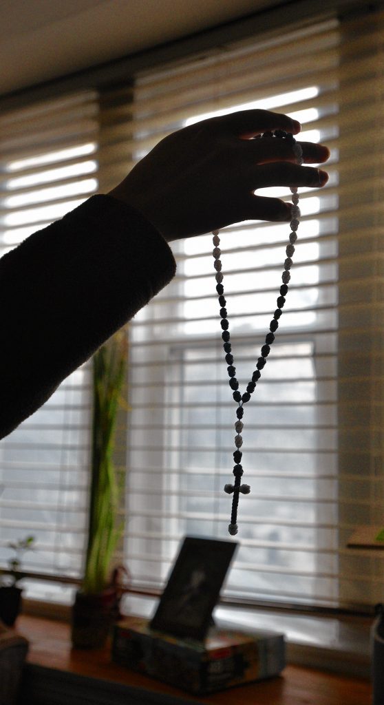 A man seeking asylum holds a crucifix at his apartment, Tuesday, Feb. 11, 2020, that a friend gave him while they were in detention together.