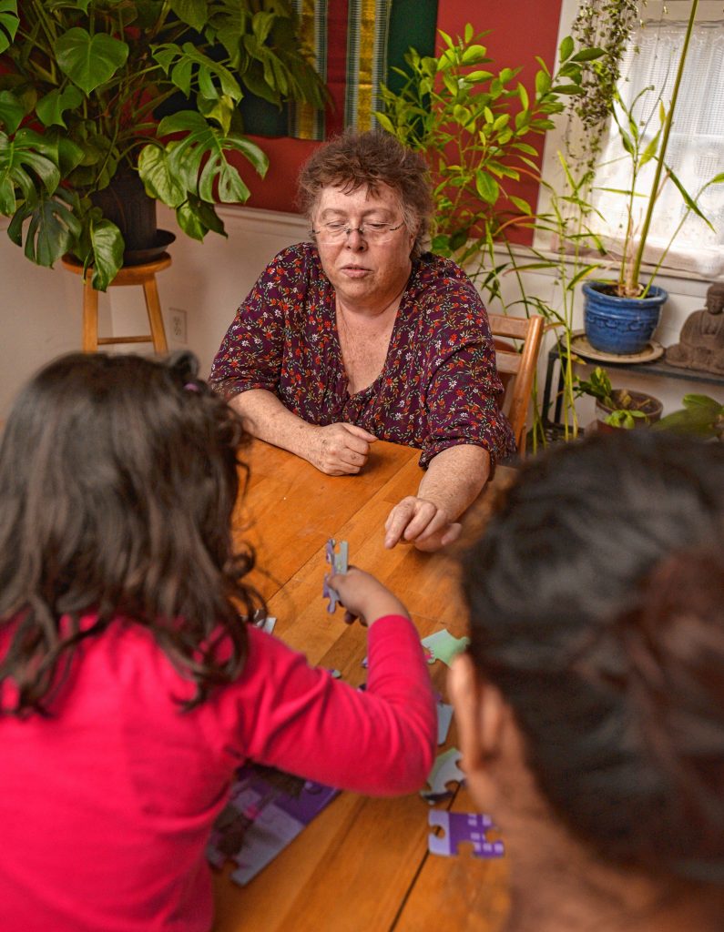 Lynne, top, talks to a woman and her 3-year-old daughter who she has given asylum to in her home, Thursday Jan. 30 as they put a puzzle together.