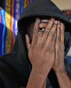 A man from west Africa who has received asylum status covers his face to hide his identity, Monday, Feb. 3, 2020.