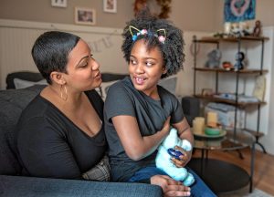 Emily Collins and her daughter, Gabrielle Collins-Hill, 8, pose in their Holyoke home with an urn containing the ashes of her son, Sebastian, who died in 2018 at the age of 2 weeks.