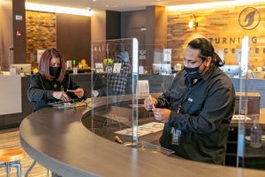 Steven Robles, team leader at Turning Leaf Centers dispensary in Northampton, shows Marketing Coordinator Nicole Desjardins how to handroll a joint.