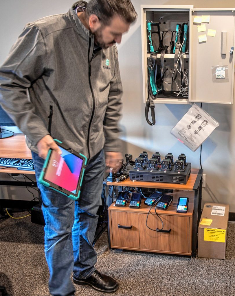 Budzee COO Volkan Polatol looks over a charging station for tablets and body cameras in the drivers' room of the cannabis delivery business's Easthampton warehouse on Friday, April 8, 2022.