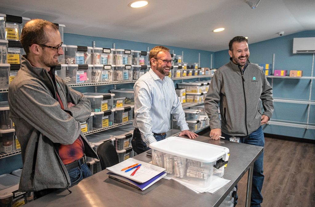 Budzee consultant Ezra Parzybok, left, CEO Kevin Perrier and Chief Operating Officer Volkan Polatol talk about their cannabis delivery business in the vault of the firm’s warehouse in Easthampton on Friday.