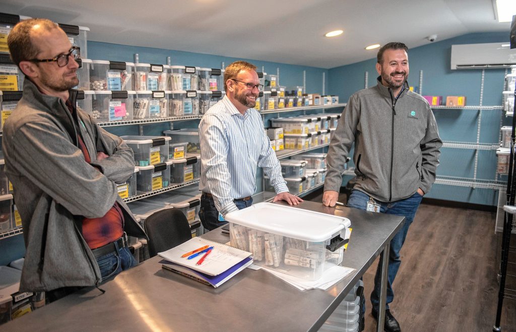 Budzee consultant Ezra Parzybok, left, CEO Kevin Perrier and COO Volkan Polatol talk about their cannabis delivery business in the vault of the firm's warehouse in Easthampton on Friday, April 8, 2022.