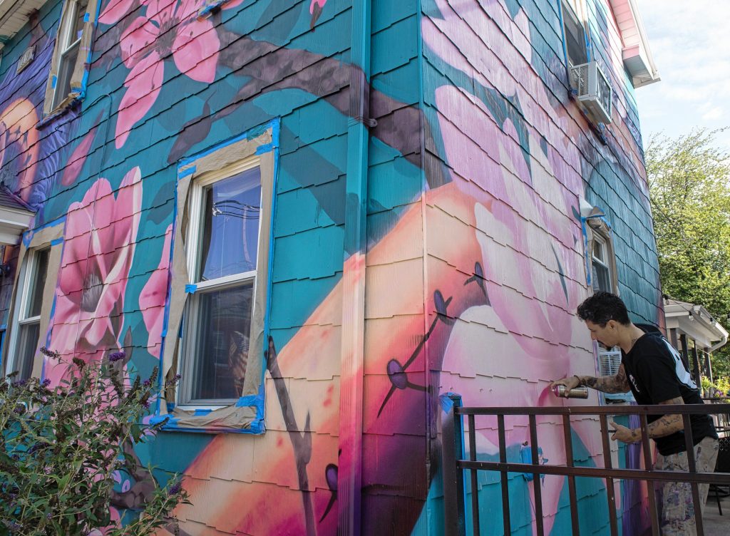 Los Angeles artist Ryan Sarfati works on a painting of a dragon on a home on Cottage Street in Easthampton. The painting is wedding anniversary gift from Easthampton resident Stephen Parmenter to his  wife Nina.