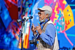 Napolean Jones-Henderson, a longstanding founding member of the African Commune of Bad Relevant Artists (AfriCOBRA), speaks Saturday afternoon during the commemoration ceremony of The Wall of Black Music mural, originally created by Nelson Stevens with his student Clyde Santana, that was recreated by Common Wealth Murals and the Community Mural Institute and is now on view at 1 Montrose Street in Springfield.