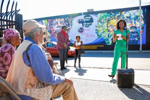 Nadya Stevens speaks Saturday afternoon during the commemoration ceremony of the Tribute to Black Women mural, originally created by her father Nelson Stevens in 1974, that was recreated by Common Wealth Murals and the Community Mural Institute and is now on view at 38 Catherine Street in Springfield.
