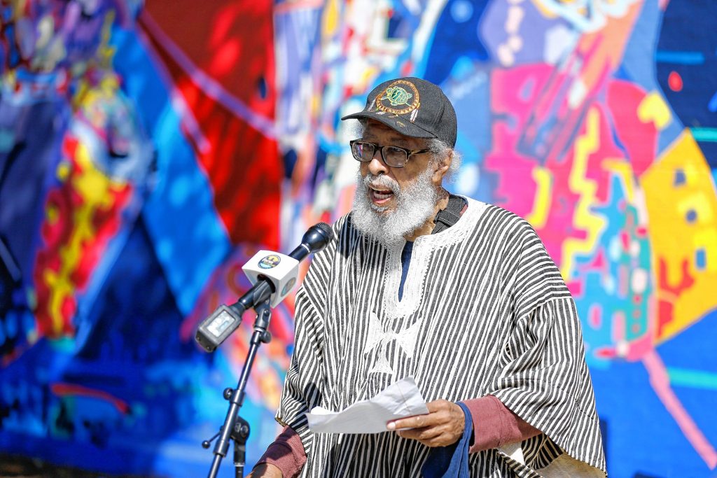 University of Massachusetts Amherst professor John H. Bracey, Jr., speaks Saturday afternoon during the commemoration ceremony of The Wall of Black Music mural, originally created by Nelson Stevens with his student Clyde Santana, that was recreated by Common Wealth Murals and the Community Mural Institute and is now on view at 1 Montrose Street in Springfield.