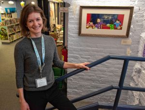 Sarah Johnson, head of Children and Young Adult services at Forbes library, stands with work by Florence artist and children’s book writer Grace Lin, titled “Bringing In The New Year – Pop!”